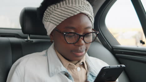 Mujer-Afroamericana-Que-Usa-El-Teléfono-Inteligente-Durante-El-Viaje-En-Automóvil